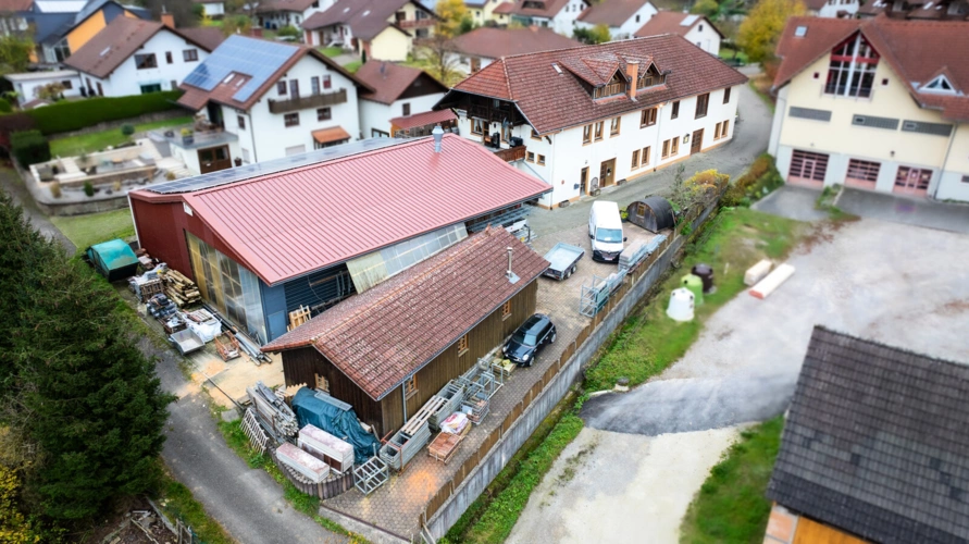 Ansicht mit Holzlager und Nebengebäude