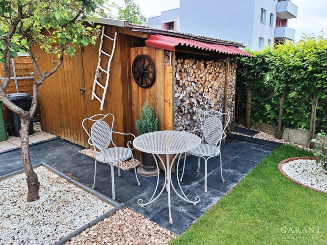 Gartenbereich mit Sitzgelegenheit und Holzlege